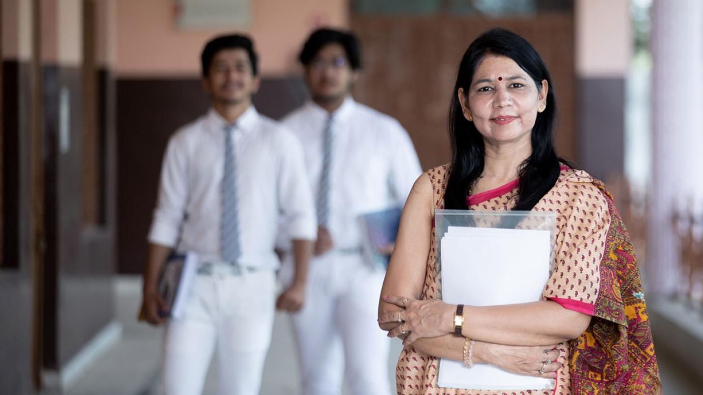 Portrait of an Indian female university professor with two students in the background